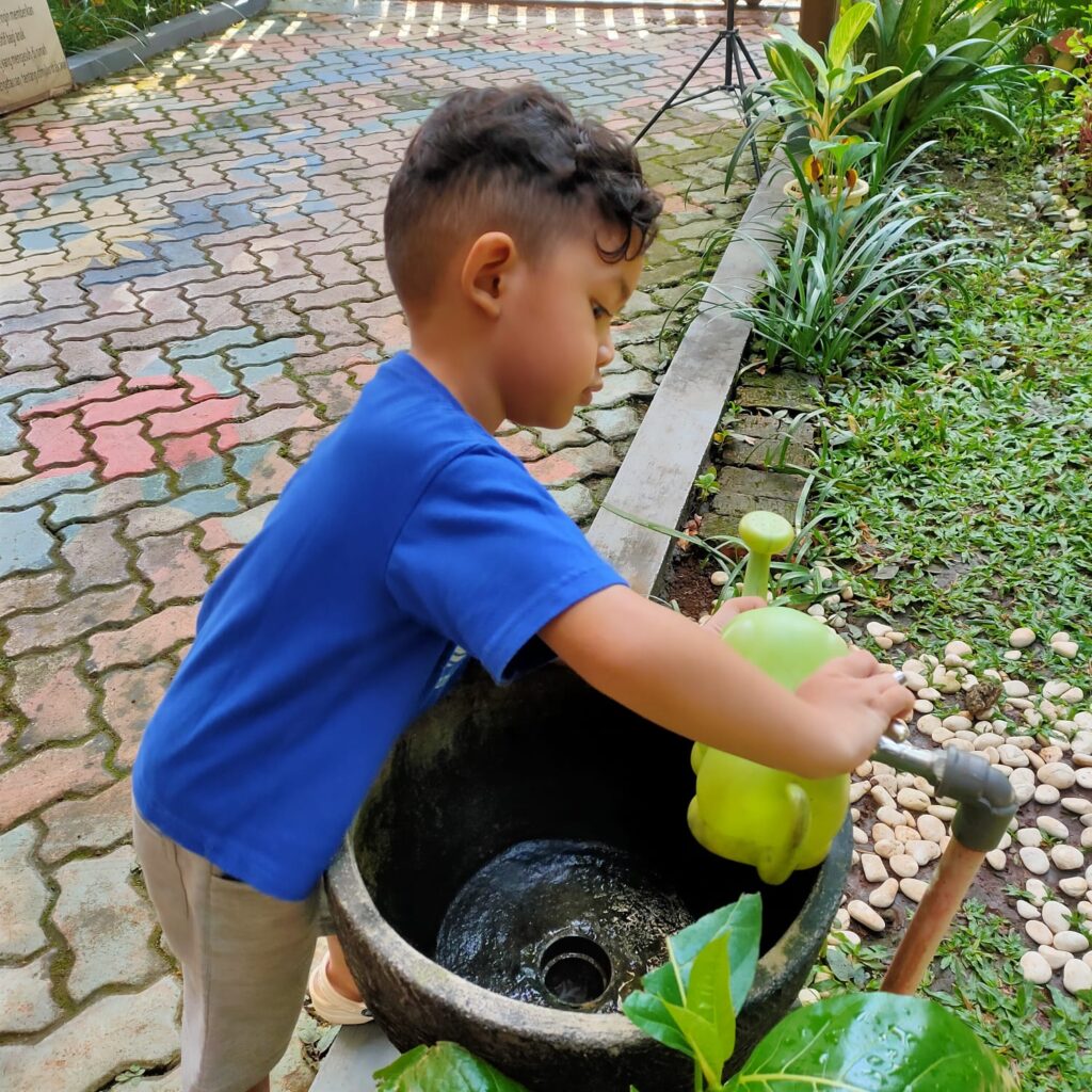 Anak menyiram tanaman di taman sekolah